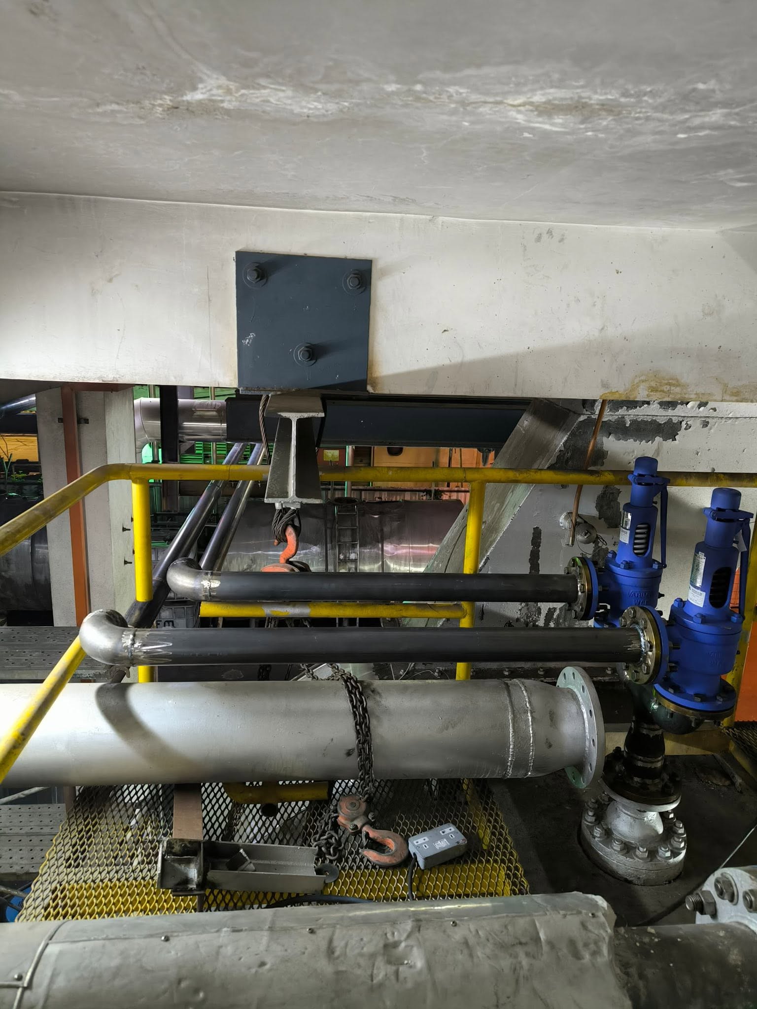 Twin blue single-port safety valves with overhead lifting beam during boiler valve conversion at Malaysian oil refinery